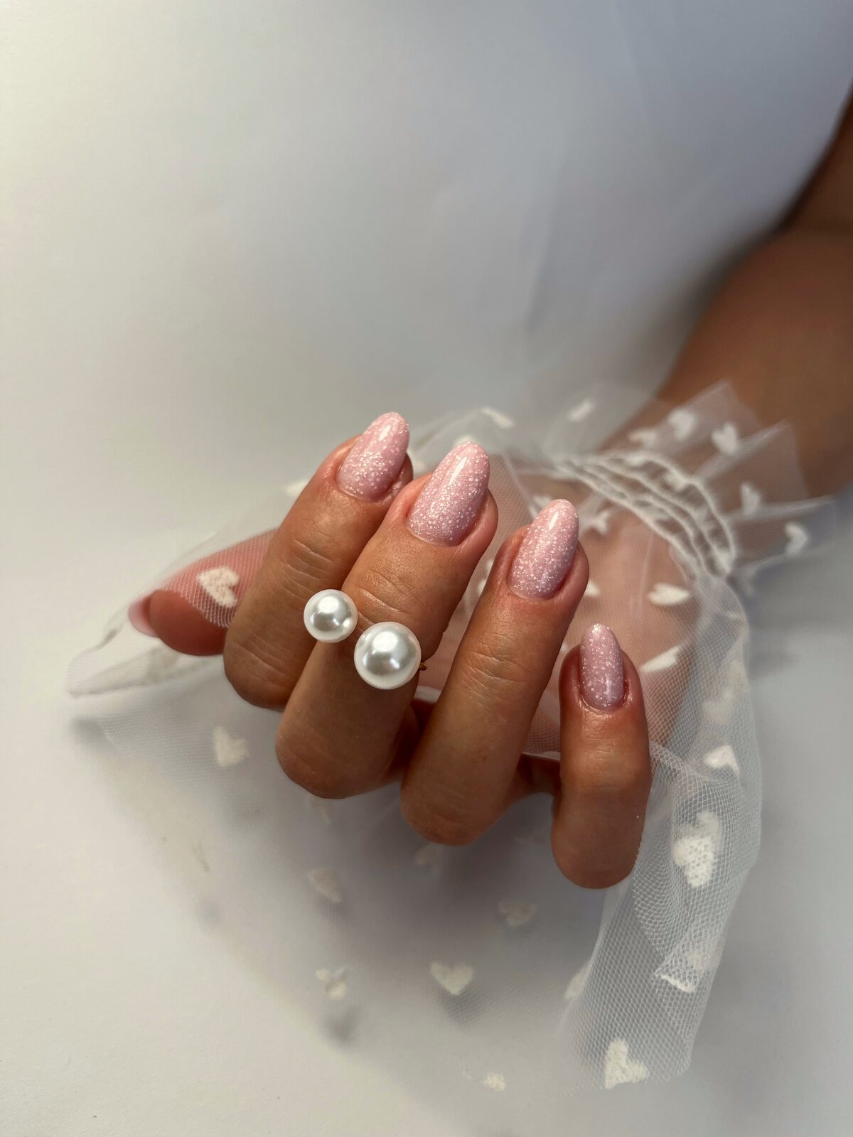 Jemný ružový glitter nail art s perlovým prsteňom